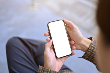 Top view of an Asian man using his smartphone while sitting at outdoor bench.