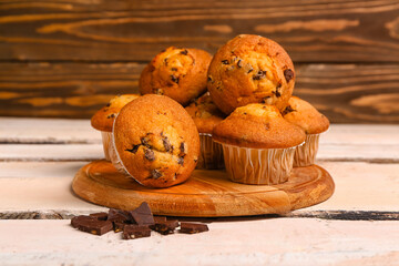 Board with delicious muffins and chocolate on white wooden table
