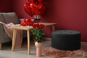 Burning candles, wine glasses and gifts for Valentine's Day on table in interior of living room