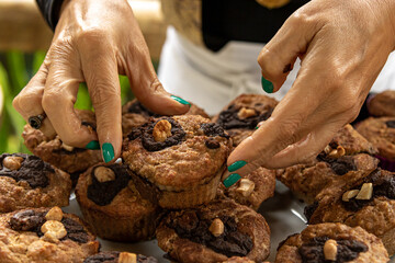 bandeja com muitos cupcakes e as mãos da chef de cozinha colocando mais um e arrumando.