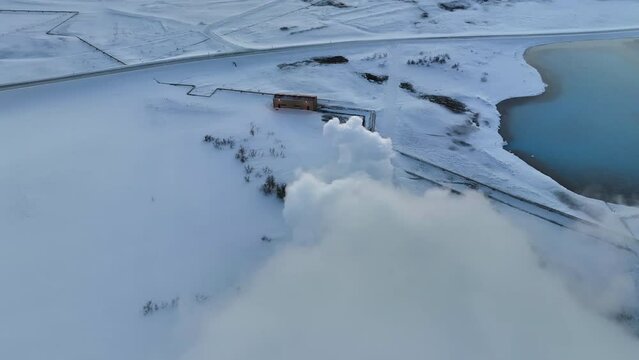 Fast drone dolly shot through the white smoke from Myvatn geothermal installations in the snowy landscape of Iceland.