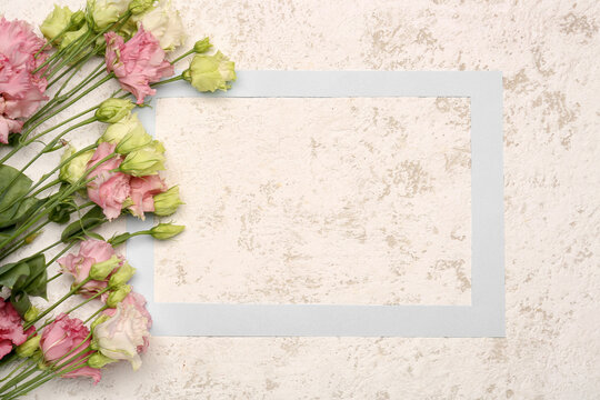 Paper picture frame and beautiful eustoma flowers on light background