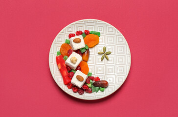 Plate with crescent and star made of sweets for Ramadan on red background