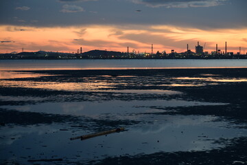 夕暮れ時の江川海岸の干潟と対岸に望む工場群