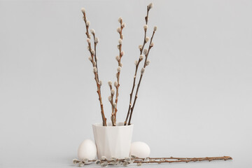 Pot with pussy willow branches and Easter eggs on grey background