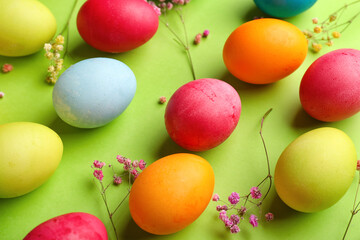 Composition with painted Easter eggs and gypsophila flowers on green background, closeup