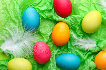 Painted Easter eggs and feathers on color crumpled paper, closeup