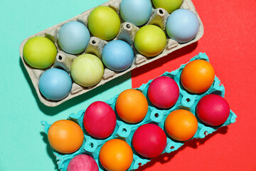 Cardboard holders with painted Easter eggs on color background, closeup