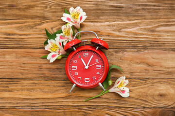 Composition with alarm clock and alstroemeria flowers on wooden background