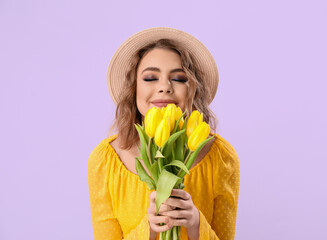 Beautiful happy young woman with bouquet of tulips on lilac background