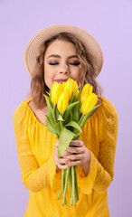 Beautiful happy young woman with bouquet of tulips on lilac background