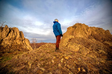 handsome mature man sits on a high rocky mountain and looks into the distance