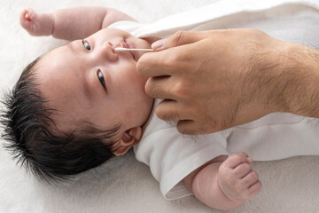 Fototapeta na wymiar 赤ちゃんの鼻を掃除する男性の手（0歳2ヶ月・日本人・男の子）