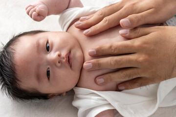Obraz na płótnie Canvas 赤ちゃんにローションを塗る男性の手（0歳2ヶ月・日本人・男の子）