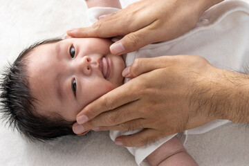 Fototapeta na wymiar 赤ちゃんにローションを塗る男性の手（0歳2ヶ月・日本人・男の子）