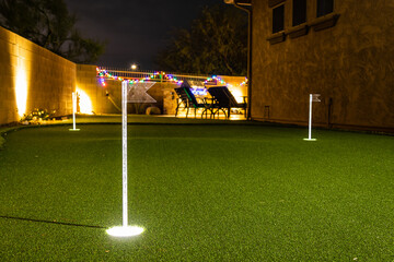 Nighttime image of a personal home putting green with illuminated holes.