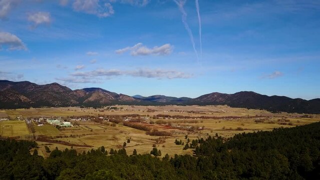 Rising over trees to reveal the town of Mora New Mexico