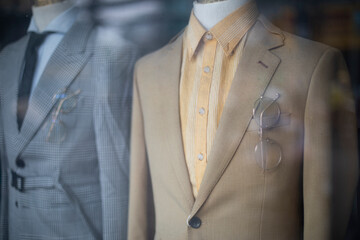 old fashioned men's suits through a shop window. Retro fashion with jackets, shirts and ties.