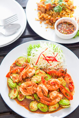 Phad Sato, stir-fried prawns with curry paste (Thai food), white plate, placed on a wooden table