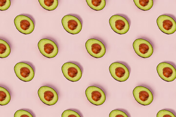 Pattern with halved avocados on pink background