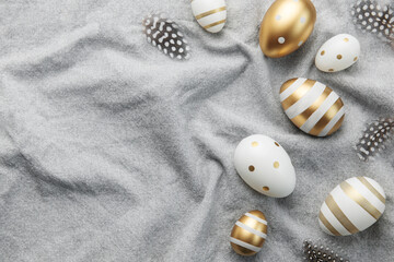 Easter eggs are painted with gold paint on a gray linen background.