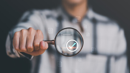 Businessman holding a magnifying glass, showing Audit Document concept,quality assessment management With a checklist, business document evaluation process, market data report analysis and consulting - obrazy, fototapety, plakaty