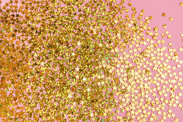 Star shaped golden glitter on pink background