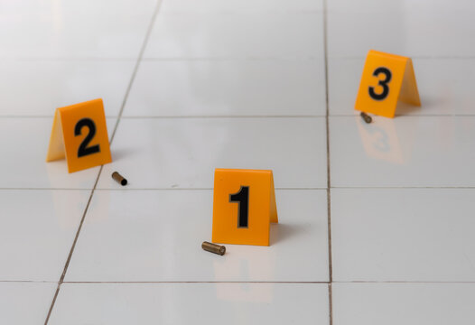 Pieces of evidence tagged by yellow markers,perspective view of shell casings and gun