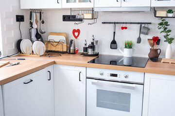 The interior of the kitchen in the house is decorated with red hearts for Valentine's Day. Decor on the table, stove, utensils, festive mood in a family nest