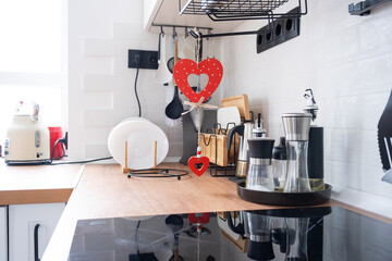 The interior of the kitchen in the house is decorated with red hearts for Valentine's Day. Decor on the table, stove, utensils, festive mood in a family nest