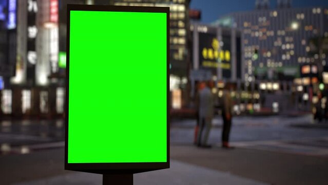 Modern billboard with a green screen for advertising on a busy crossroad street with traffic and skyscrapers, timelapse of traffic at night. Loop video.