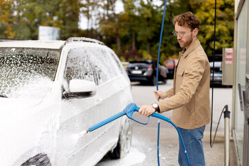 Man cleaning his car with high pressure water. Self-service car wash concept 