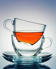 Two glass transparent cups with tea and saucers on a white-blue gradient background. Tea break.Morning tea drinking.