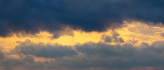 Dark storm clouds illuminated by the bright evening sun, panorama