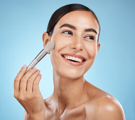 Cosmetics, thinking and woman with a brush for makeup isolated on a blue background in studio. Skincare, beauty and model happy about cosmetology, foundation and body health on backdrop with a smile