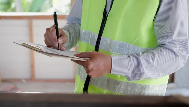 inspector or engineer is inspecting construction and quality assurance new house using a checklist. Engineers or architects or contactor work to build the house before handing it over to the homeowner