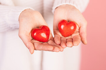 closeup hands holding heart on pink background, valentine's day concept