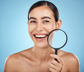 Face skincare, magnifying glass and beauty of woman in studio isolated on a blue background. Facial portrait, makeup and cosmetics of female model with magnifier lens to check aesthetic wellness.