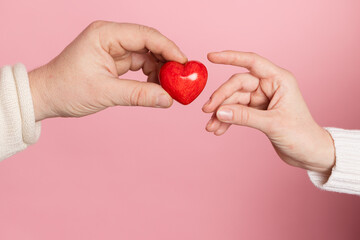 closeup hands holding heart on pink background, valentine's day concept