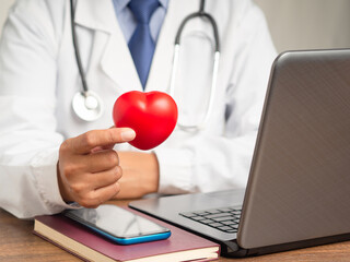 Cardiology specialist treatment. Close-up of hand holding a red heart shape symbol while sitting in the hospital