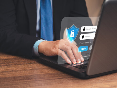 Businessman in a suit login to the network by username and password on the virtual screen while sitting at the table in the office