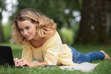 woman working with her notebook lying on a lawn