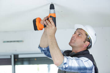 construction worker assemble a suspended ceiling with drywall