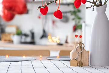 Key to house of cozy home with Valentine decor on table of kitchen. Gift for valentines day, family love nest. Building, design, project, moving to new house, mortgage, rent and purchase real estate