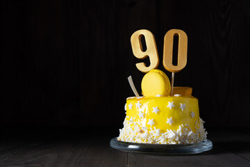 The number Ninety on a yellow cake for an anniversary or birthday in a dark key.