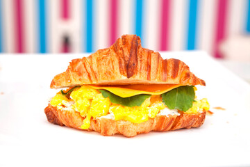 Breakfast brioche croissant sandwich with scrambled egg filling cheese and rocket leaf.