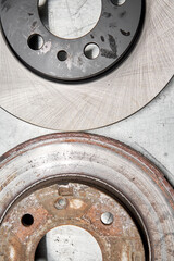 Old rusty brake disc and new disc. Change the old to new brake disc on car in a garage. Auto repair concept.