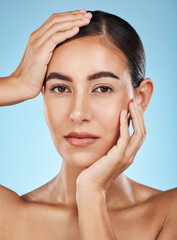 Naklejka premium Portrait, beauty and hands with a model woman in studio on a blue background for natural skincare. Face, skin and cosmetics with an attractive young female posing to promote a luxury product