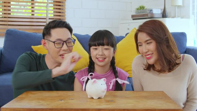 Asian family teach Asian daughter saving money putting coins into piggy bank. education, save money, Asian family, investment, future investment or family relationship concept.