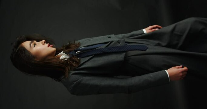 young business lady in jacket and pants posing on black background. vertical video
